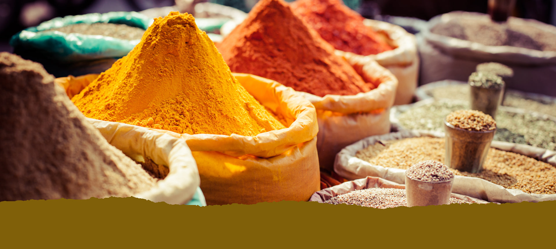 Eine Reihe großer Papiersäcke mit bunten Gewürzen auf einem Großmarkt. Text: Unsere Bestseller