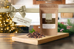 JKR Spices Nelken ganz im Doypack als Geschenkidee, Gewürzpackung auf Holzbrett mit Weihnachtsdeko und Lichterkette