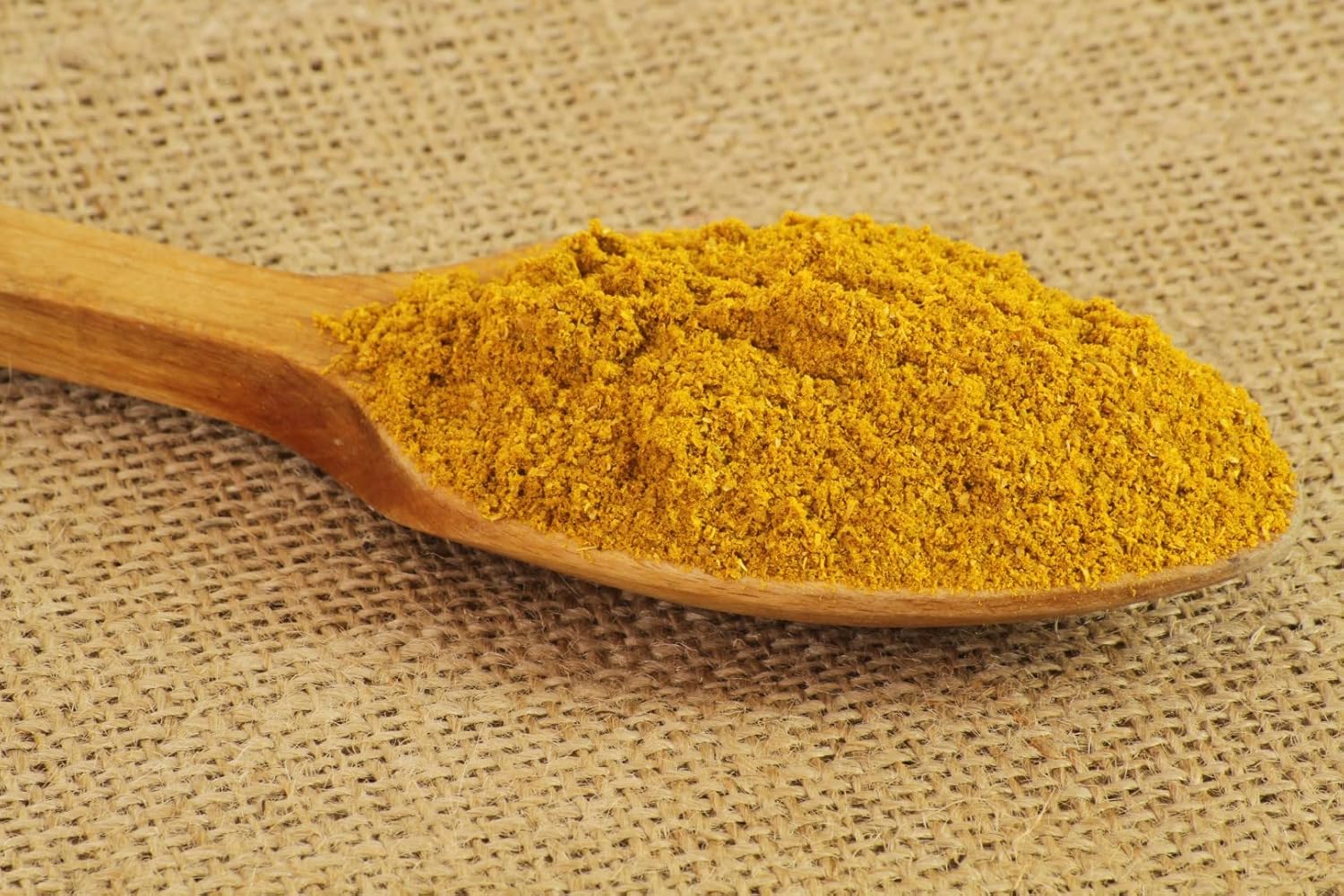 Ras el-Hanout Gewürzpulver auf Holzlöffel, orientalische Gewürzmischung als Detailaufnahme, Anwendung und Zutatenmotiv