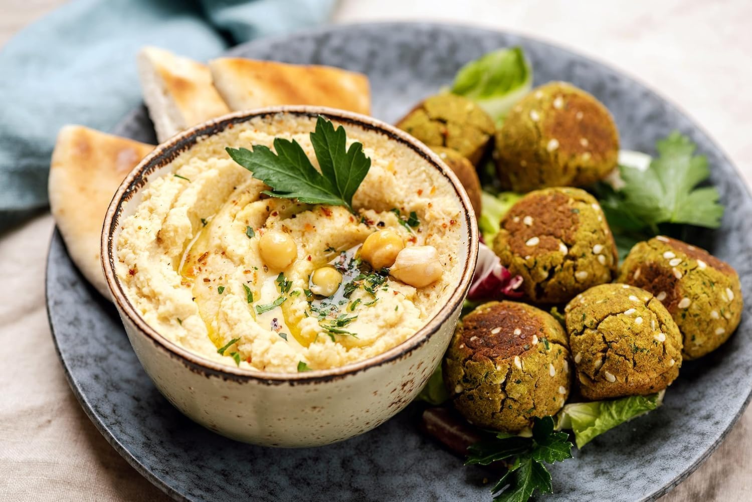 Serviervorschlag Koriander: Hummus mit Olivenöl und Kichererbsen, Falafel und Fladenbrot, mit Kräutern garniert
