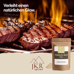 JKR Spices Alabama Beef Rub im Doypack vor gegrilltem Steak mit Flammen, BBQ Werbebild für Rindfleisch Gewürzmischung