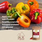 Rote, grüne, gelbe und orange Paprikaschoten auf einer braunen Holzfläche. Text: Aus Liebe zum Produkt/Sorgfältig ausgewählt/Schonend verarbeitet/Fair gehandelt
