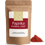 JKR Spices Paprika Smoked „mild“ im braunen Doypack, geräuchertes Paprikapulver als roter Gewürzhaufen vor weißem Hintergrund