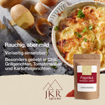 Eine weiße Auflaufform mit Kartoffelgratin, daneben einige geschälte Kartoffeln und ein Schälmesser. Text: Vielseitig einsetzbar/Besonders geliebt in Chili, Grillgerichten, Tomatensoßen und Kartoffelgerichten