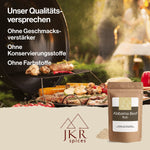 JKR Spices Alabama Beef Rub im Doypack vor BBQ Grillmotiv mit Gemüse und Fleisch, Werbebild mit Qualitätsversprechen ohne Geschmacksverstärker, Konservierungsstoffe und Farbstoffe