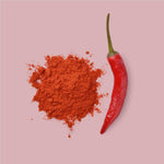 Fein gemahlenes Chilipulver mit frischer Chilischote auf rosa Hintergrund – scharfes Gewürz in dekorativer Darstellung