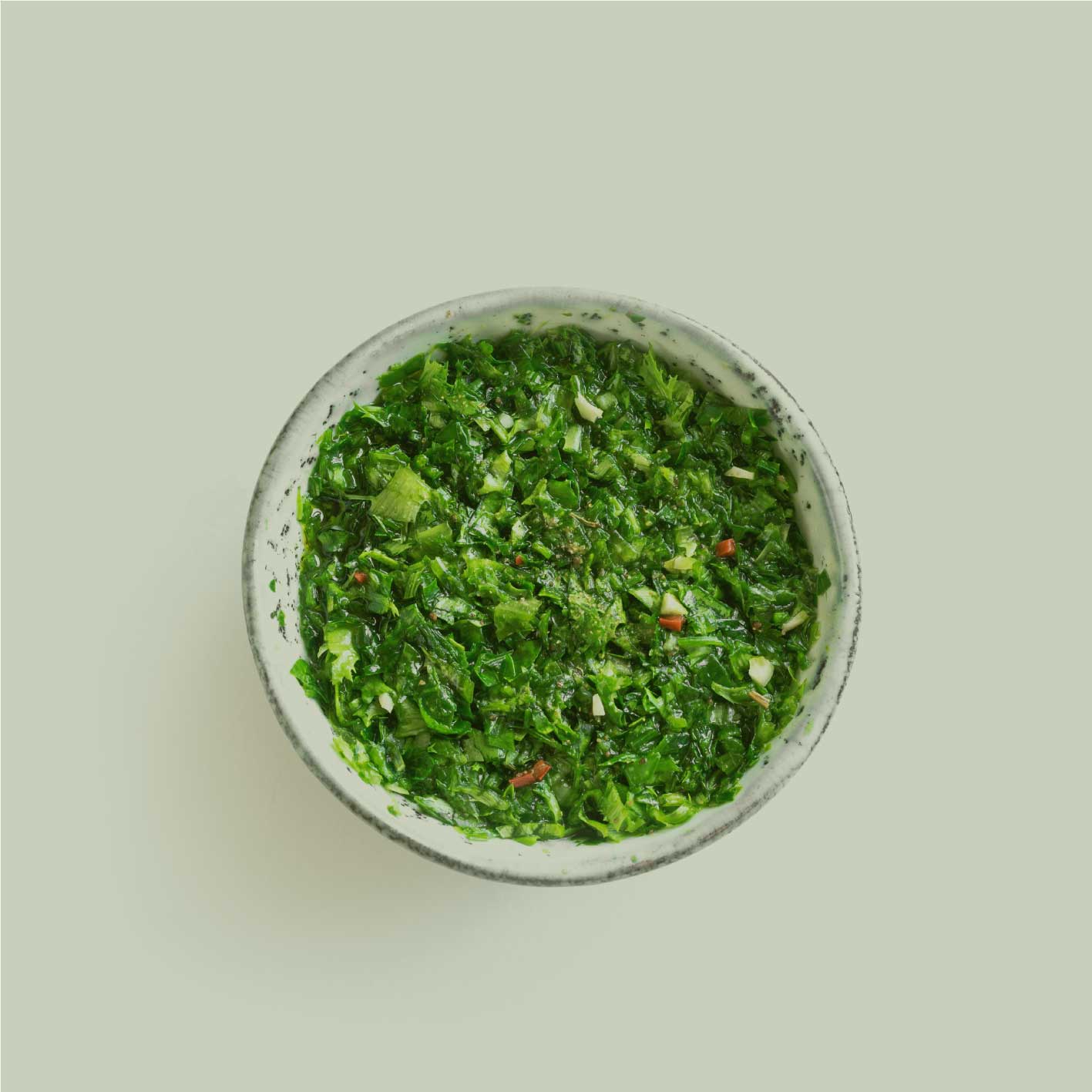 Frische, fein geschnittene Chimichurri-Kräuter in einer Schale von oben – grüne Kräutermischung in natürlicher Darstellung