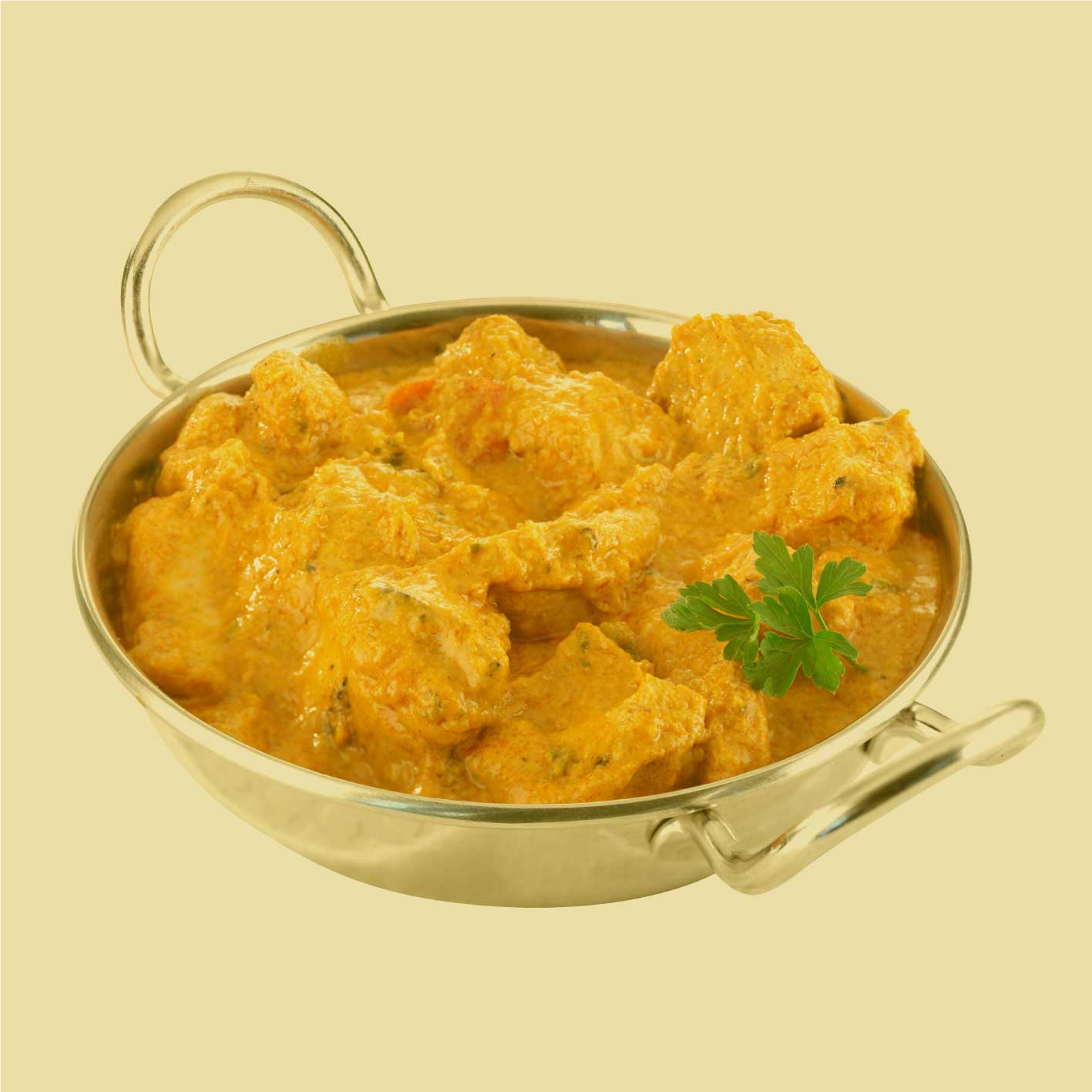 Englisch Curry als cremiges Gericht in einer Metallpfanne – serviert mit frischer Petersilie auf hellem Hintergrund