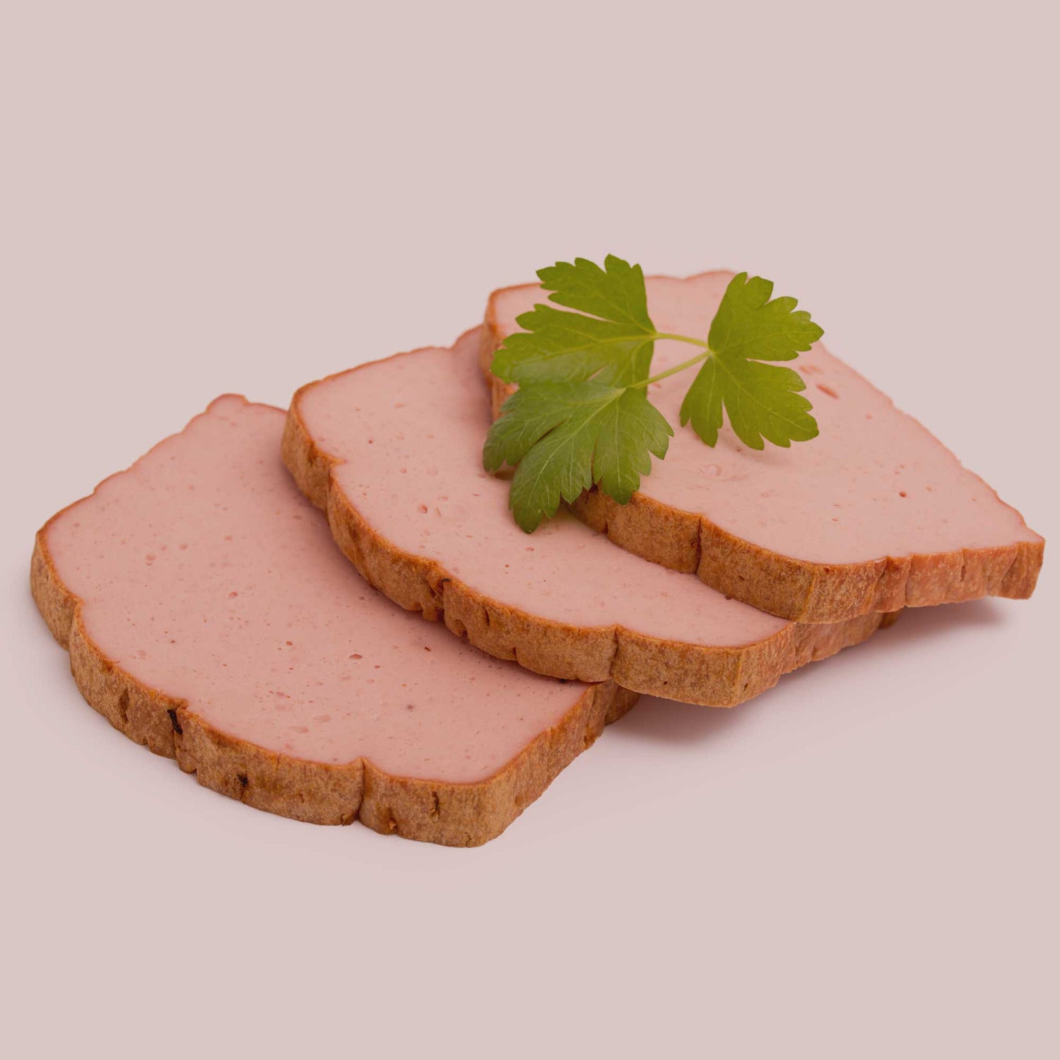 Frische Leberkäsescheiben auf hellem Hintergrund, garniert mit Petersilie – Beispiel für die Anwendung der Gewürzmischung